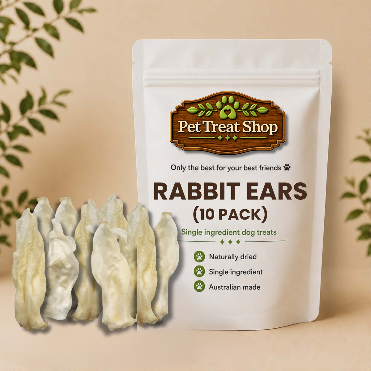 A stand-up pouch of Pet Treat Shop Rabbit Ears dog treats on a beige background with decorative leaves. The white pouch shows the brand logo and text 'RABBIT EARS (10 PACK)'.